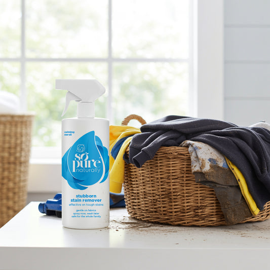 Bottle of 'so pure' stain remover on a table with a wicker basket of clothes in the background.